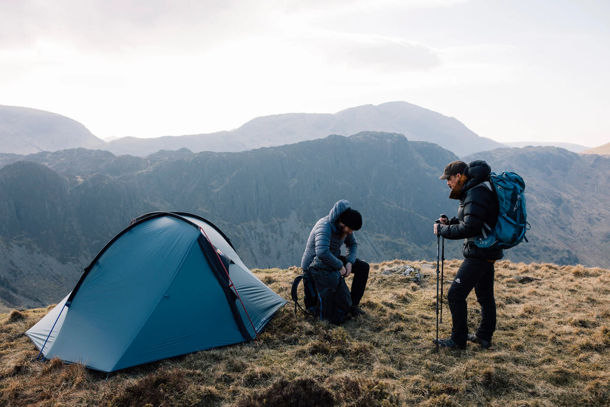 Two backpackers stood alongside the Wild Country Helm Elite 1 on a mountain