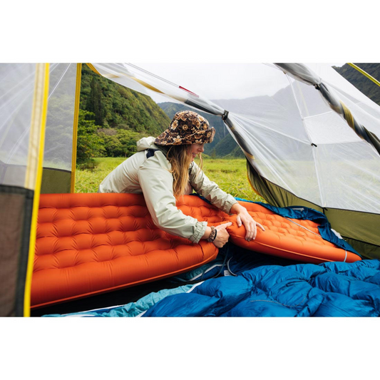 Someone putting a red sleeping mat in a tent