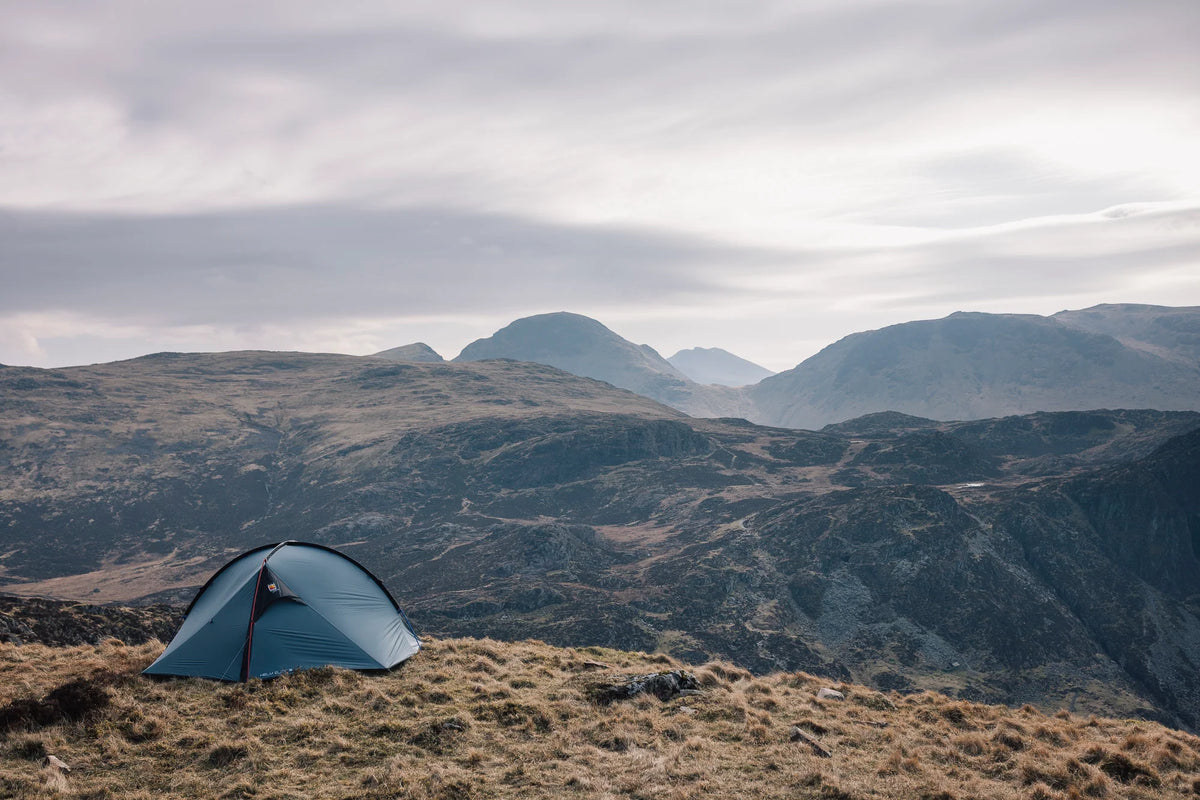 A three-person tent pitched in the hills