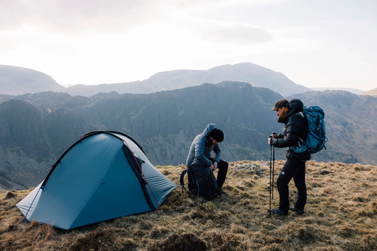 Two backpackers stood alongside the Wild Country Helm Elite 1 on a mountain
